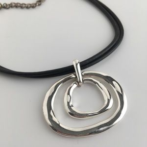 Black corded necklace with silver metal pendant.
